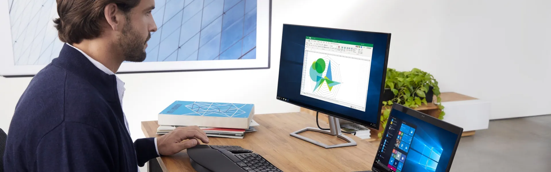 Masasında Windows dizüstü ve masaüstü bilgisayarla çalışan kişi